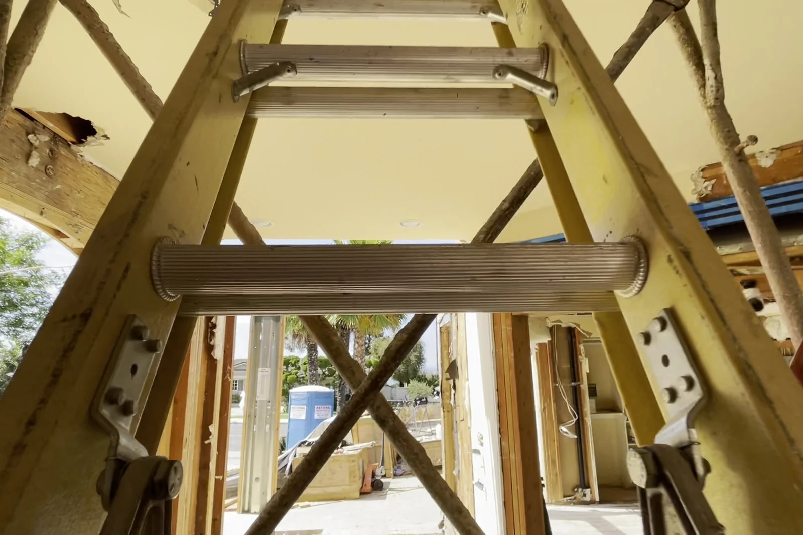 New multi-ply beams and posts carrying the ceiling where interior walls used to stand, with temporary shoring still in place beneath