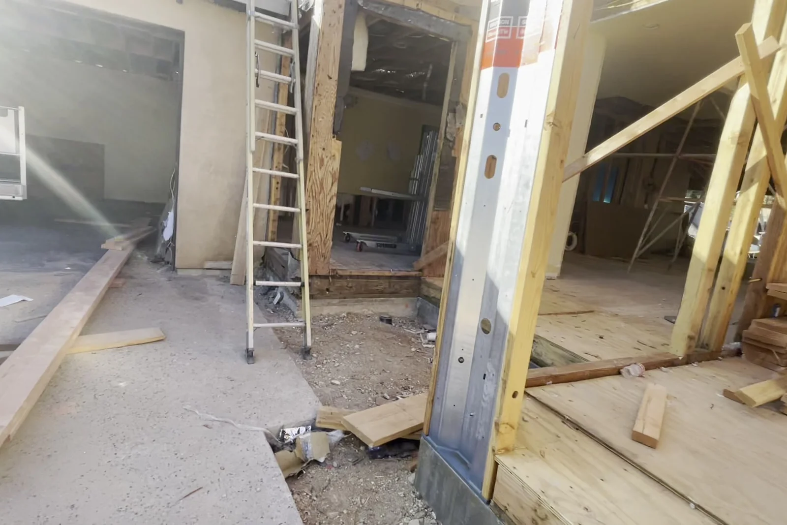 The main floor stripped back to timber, a ladder standing in the middle of the open room and daylight coming through a protected window opening