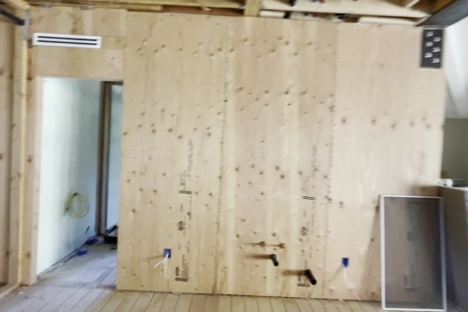 A full plywood wall panel sheathed and nailed off, with anchor hardware set at the base of the panel